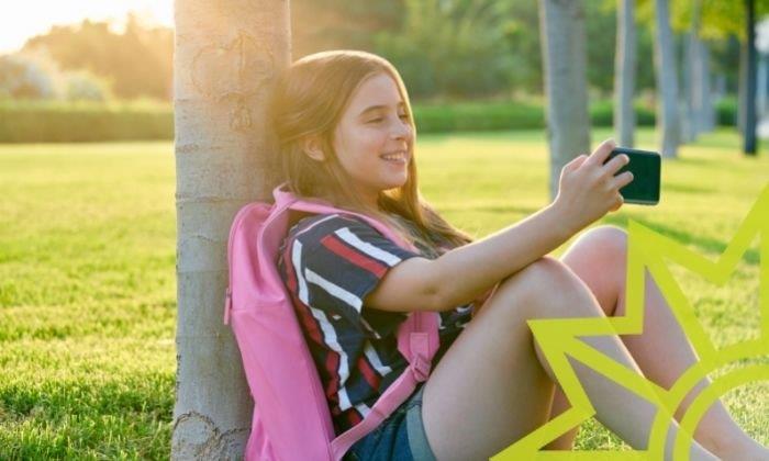 Schülerin hält das erste eigene Smartphone in der Hand