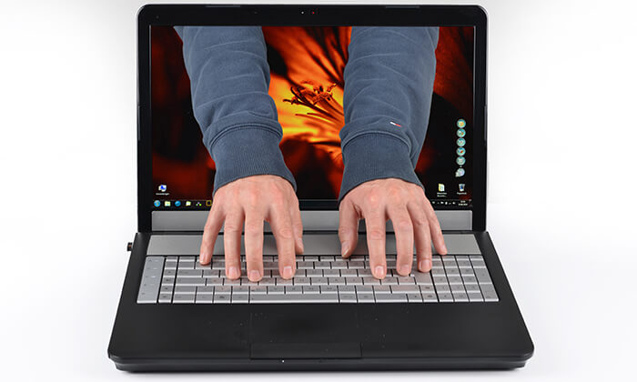 Hände übernehmen aus dem Bildschirm eines Notebnooks heraus die Tastatur.