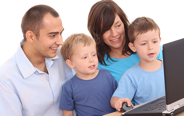 Eltern mit zwei Kindern vor einem Rechner