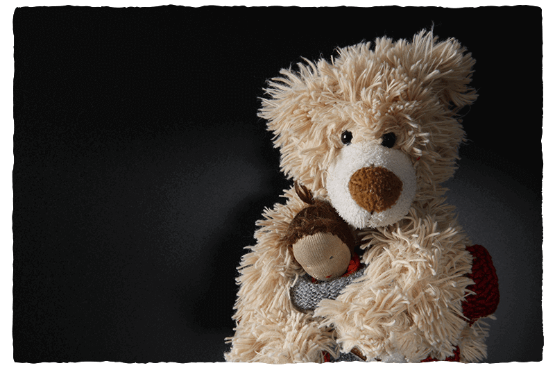 Missbrauch verhindern: Bären-Motiv. Teddy-Bar hält Puppe im Arm.