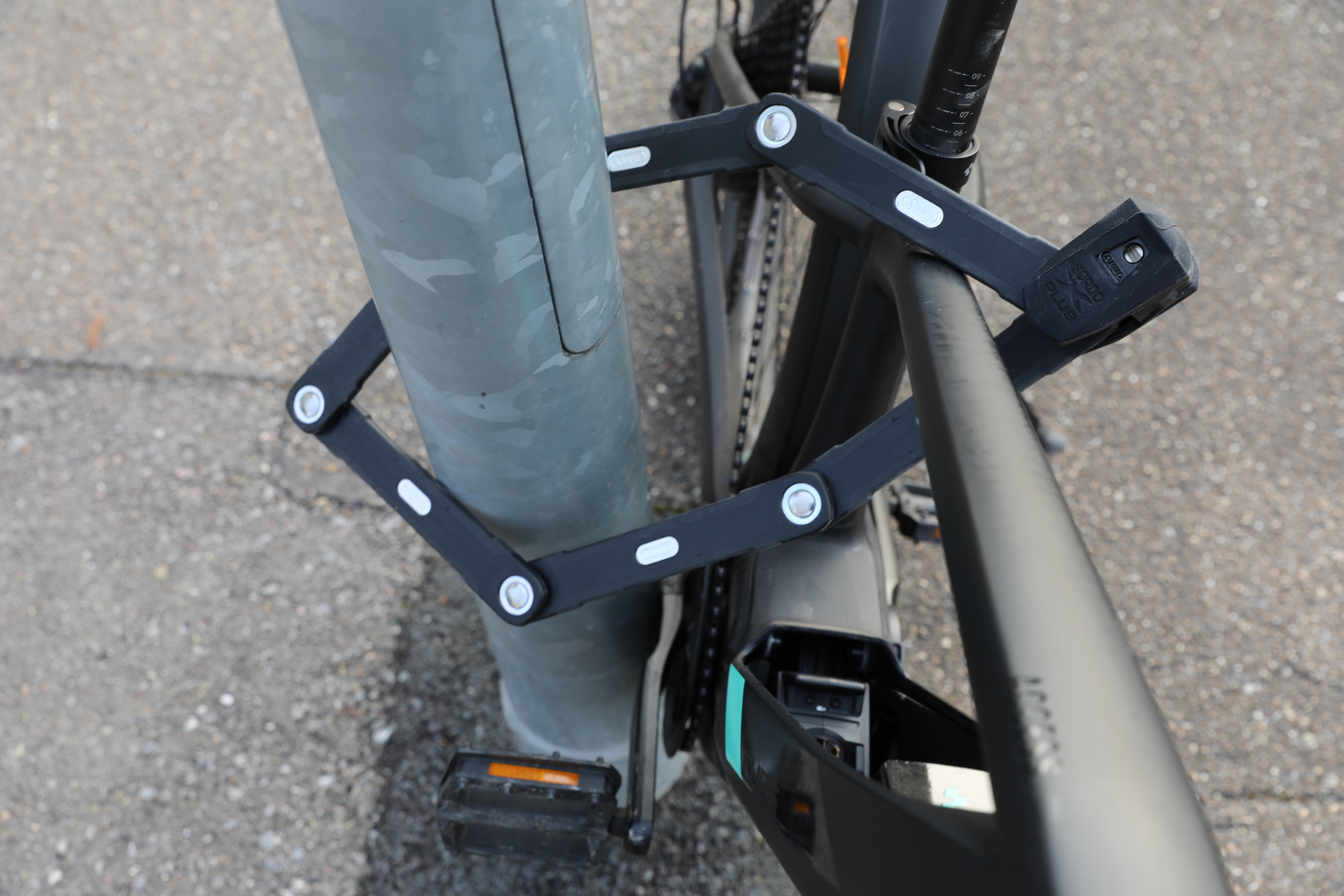 E-Bike Rahmen mit Faltschloss gesichert an Laternenpfahl.
