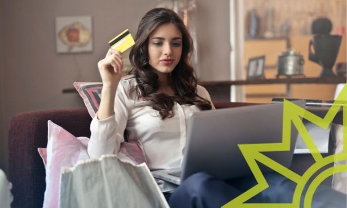 Junge Frau mit einer Kreditkarte sitzt vor dem Computer