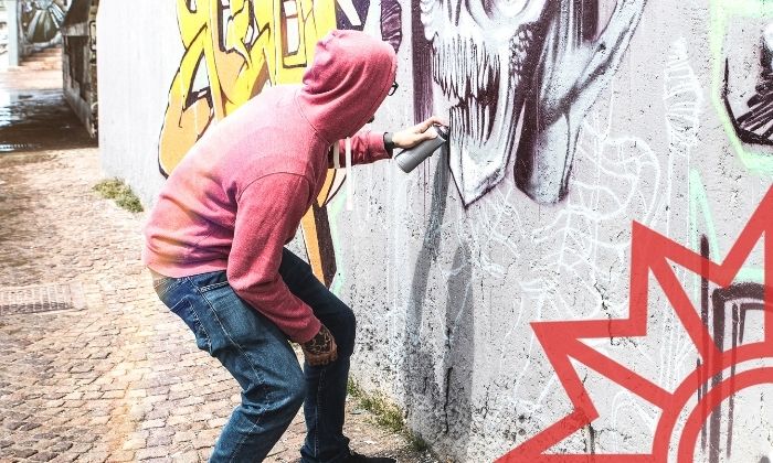 Graffitisprayer besprüht eine Wand.