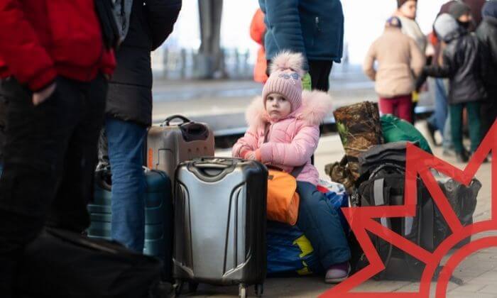 Flüchtlinge aus der Ukraine. Kind sitzt auf gepackten Koffern am Bahnsteig.