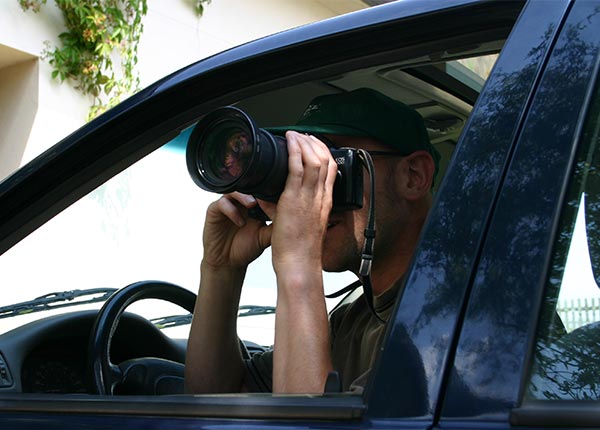 Mann mit Kamera fotografiert aus dem Autofenster heraus.