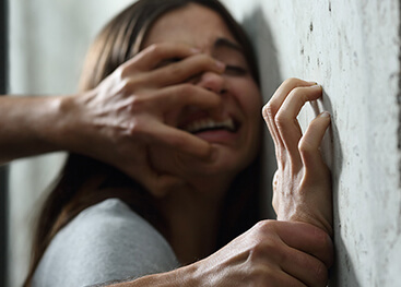 Ein Mann drückt ein Mädchen gewaltsam an eine Wand.