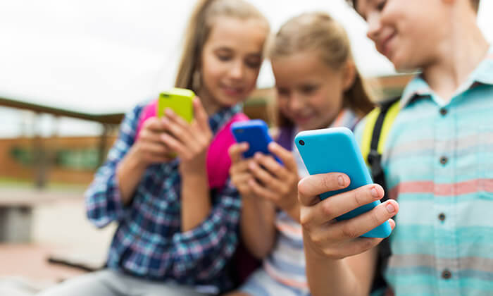 Medienkompetenz, Mädchen schauen auf ihre Smartphones und unterhalten sich darüber