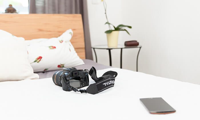 Wertsachen, wie Tablet und Kamera, auf einem Hotelbett.