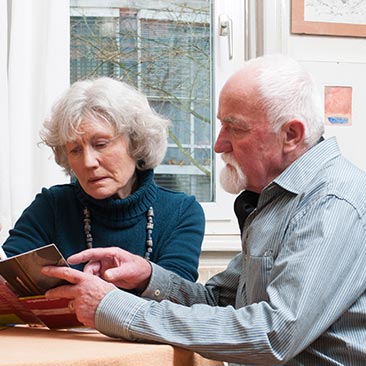 Senioren-Paar schaut gemeinsam eine Broschüre an.