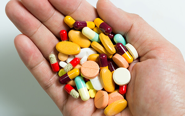 Medikamente: Geöffnete Hand mit vielen bunten Pillen