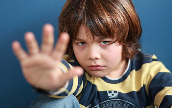Ein Junge mit resigniertem Blick zeigt mit seiner Hand die Stoppgeste.