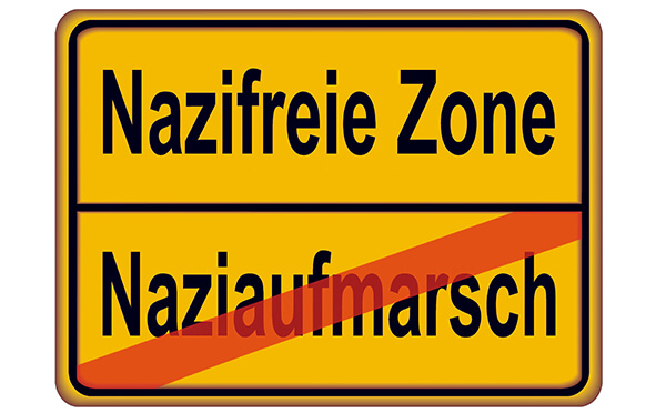 Ein "Verkehrsschild" weist auf die "nazifreie Zone" hin; das Wort "Naziaufmarsch" ist durchgestrichen