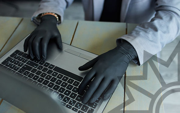 Mann mit Handschuhen am Laptop