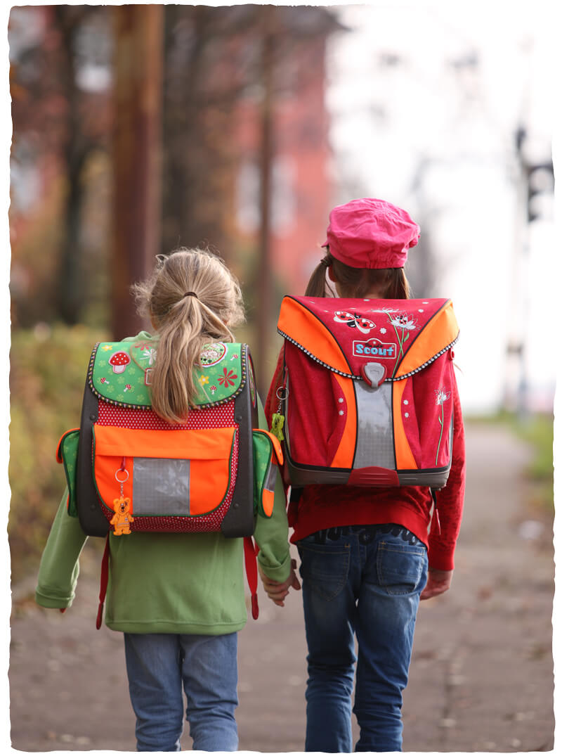 Zwei Mädchen mit Schulranzen auf dem Weg zur Schule.