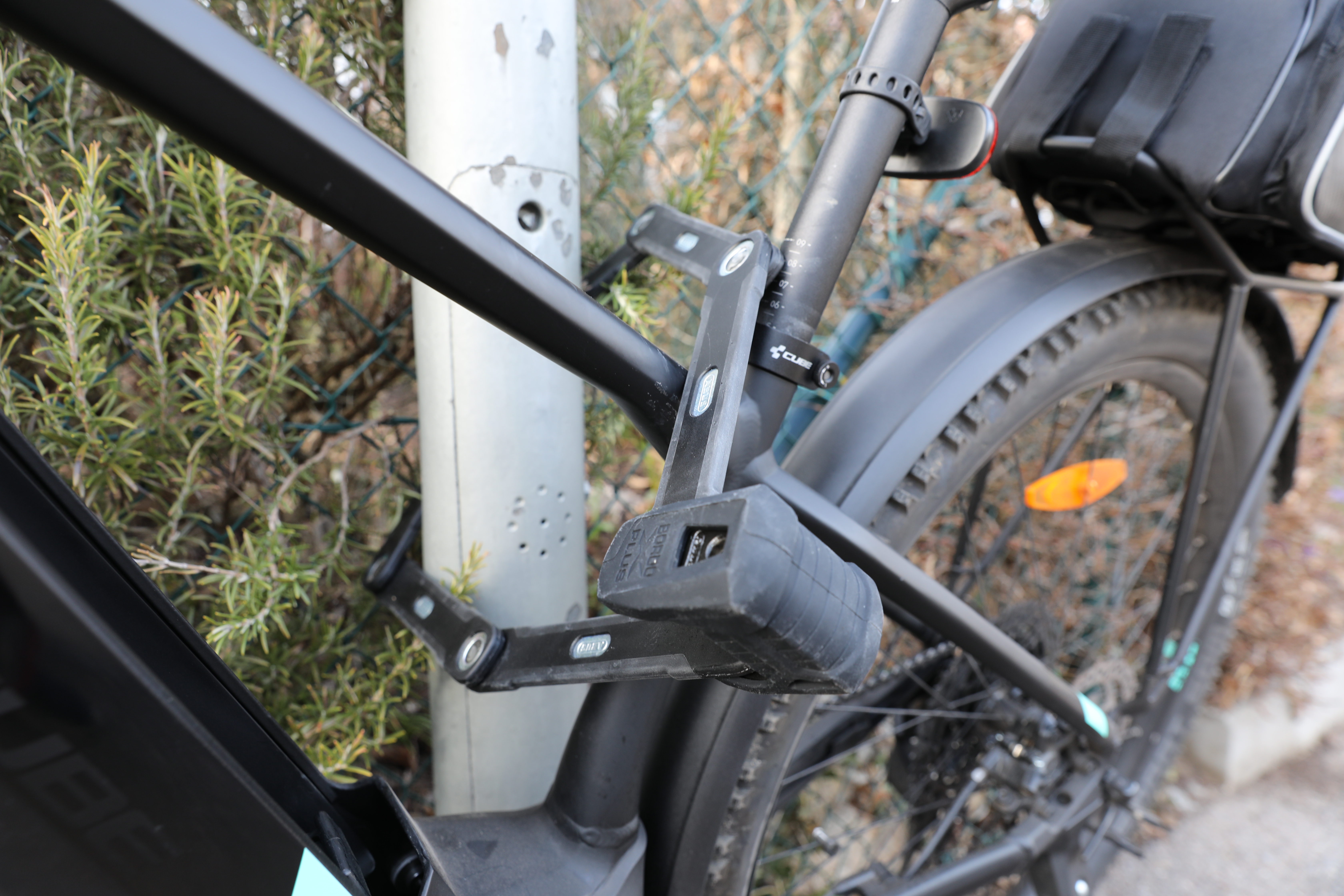 E-Bike mit Faltschloss gesichert an fest verankertem Pfahl.