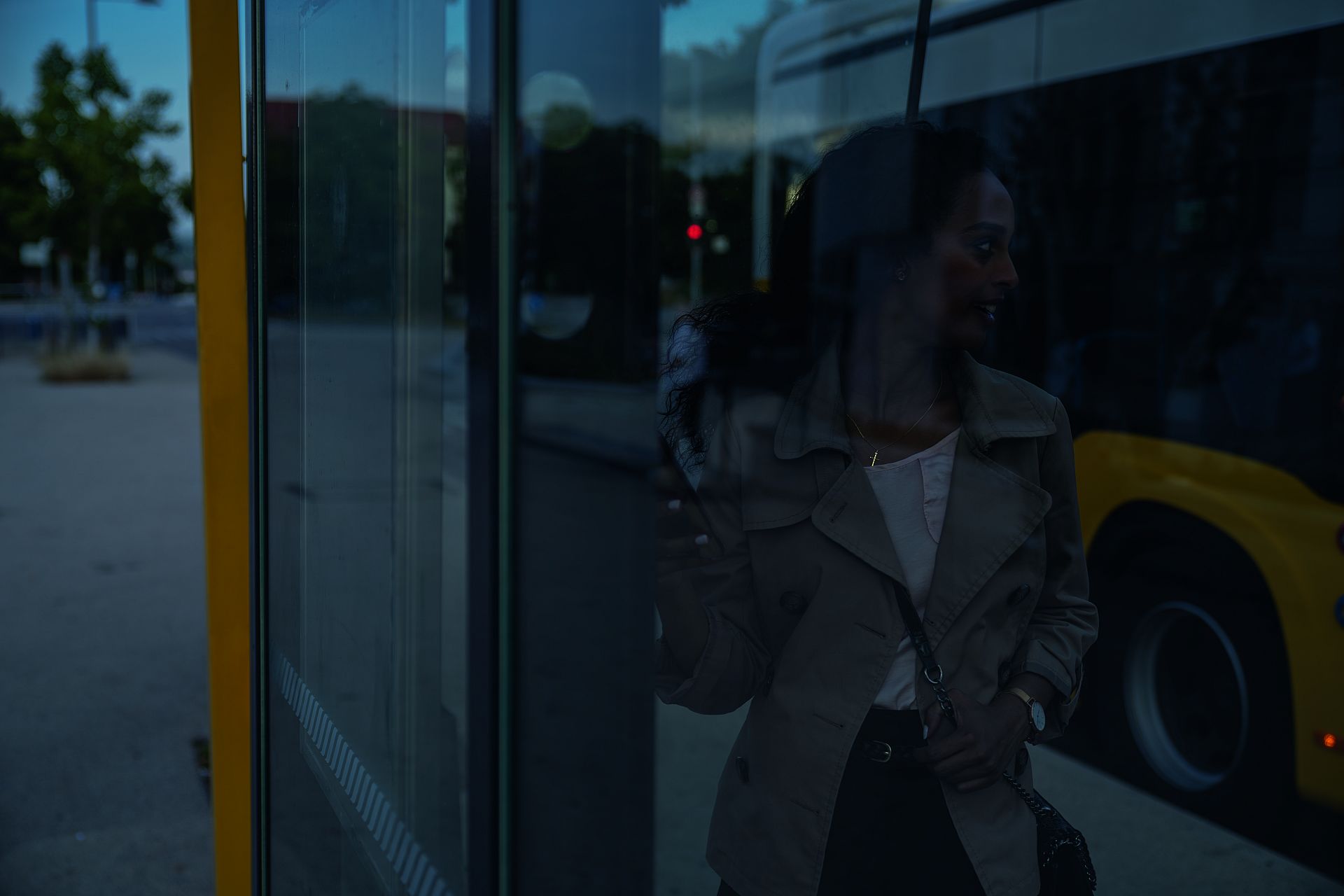 Eine Frau wartet an der Bushaltestelle in der Dämmerung.