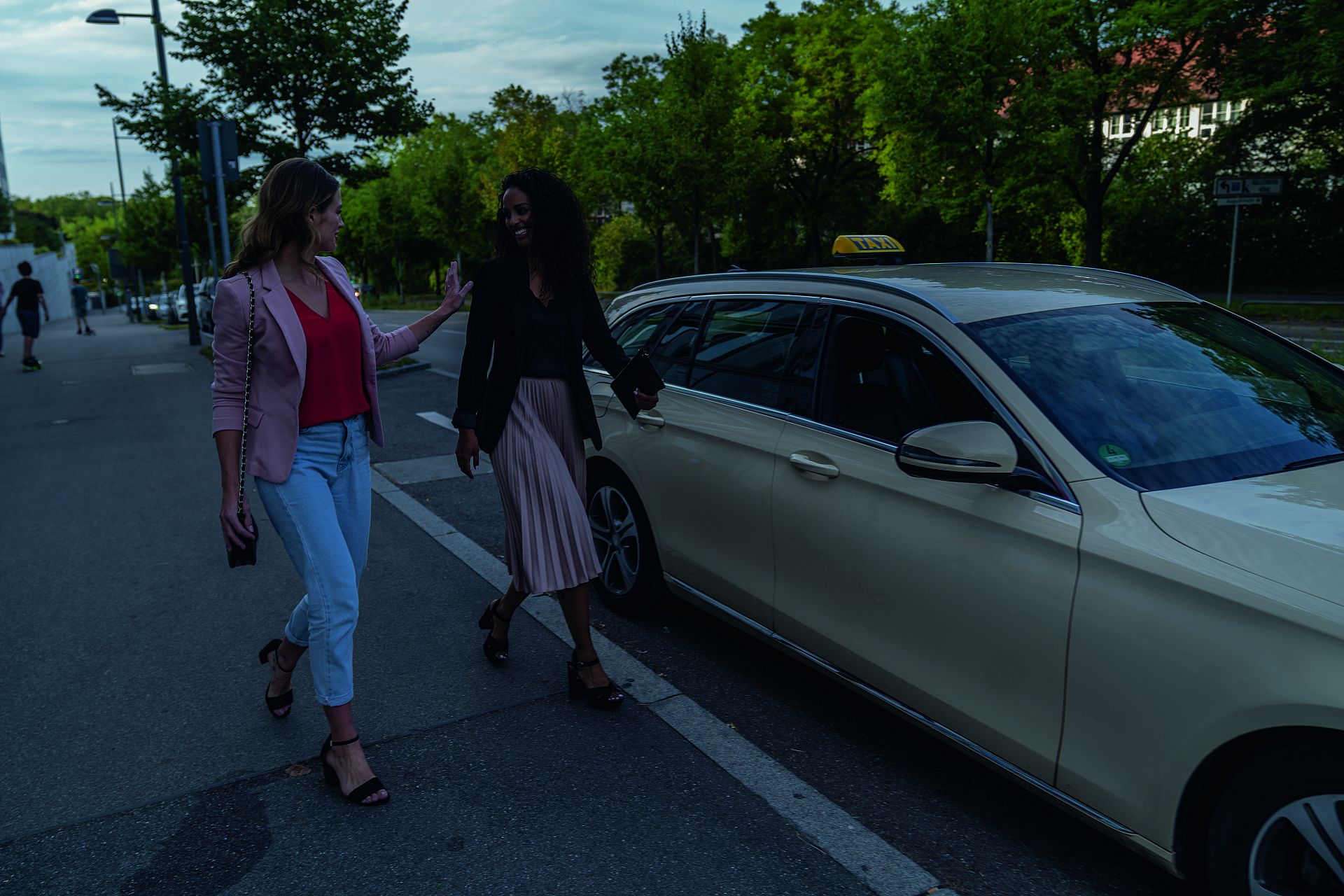 Zwei junge Frauen in der Abenddämmerung am Taxistand.