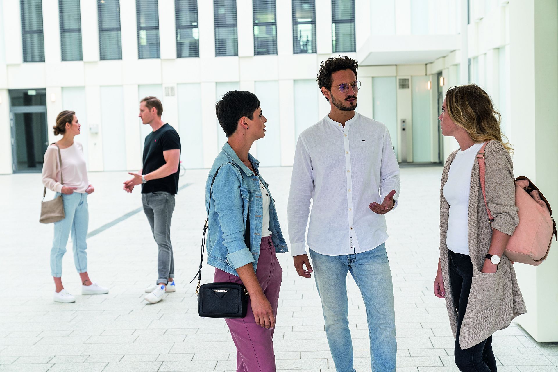 Eine Gruppe junger Leute steht in einem Innenhof eines größeren Gebäudekomplexes.