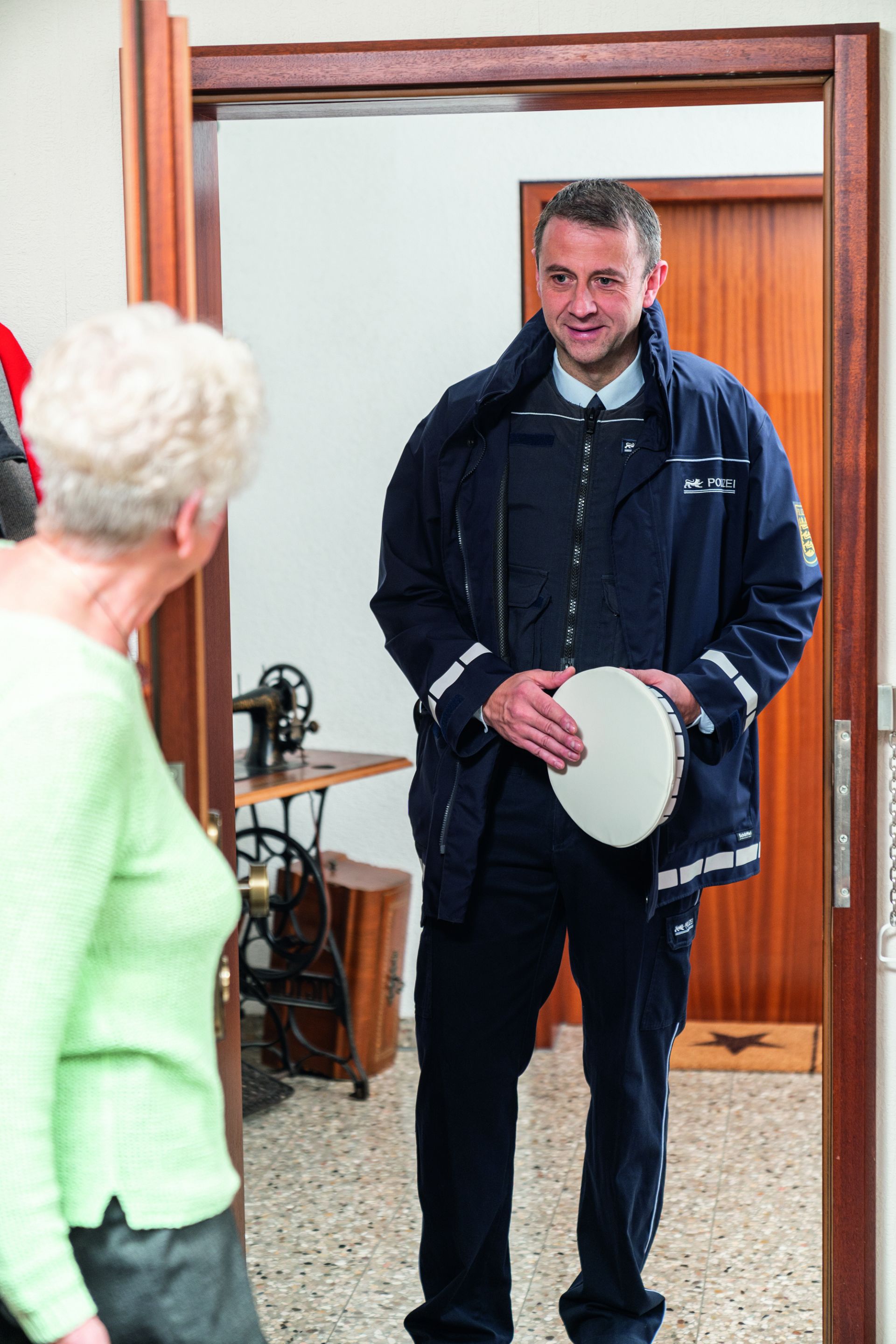 Polizeibeamter vor der Wohnungstüre einer älteren Dame.