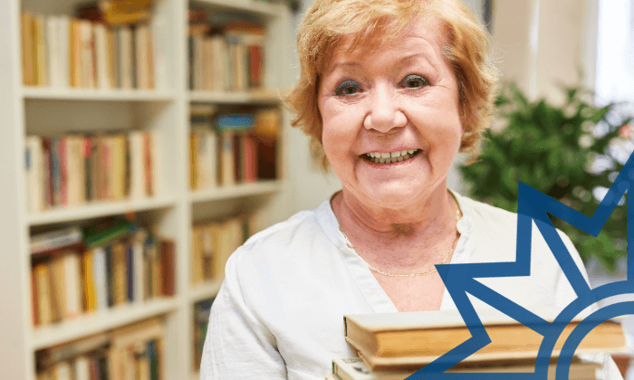 Porträt einer lächelnden älteren Frau vor einem Bücherregal. Sie hält mehrere Bücher in den Händen. Rechts im Bild ist ein blaues, grafisches Sternsymbol eingeblendet.