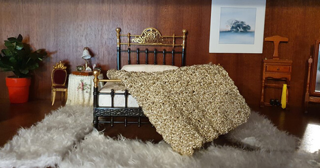 Symbolisches Miniaturzimmer mit Bett, Nachttisch, Lampe und Teppich, das eine geschützte Umgebung für Prostitution darstellt.