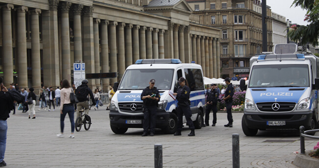 Zwei Polizeifahrzeuge stehen gut sichtbar auf einem belebten Platz im Bahnhofsviertel. Mehrere Polizeibeamtinnen und -beamte sind vor Ort im Einsatz. Im Hintergrund befinden sich historische Gebäude und Passanten.