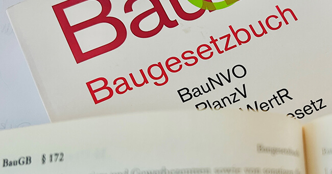 Nahaufnahme eines aufgeschlagenen Buchs mit dem Titel „Baugesetzbuch“ und hervorgehobenen Paragraphen, die sich mit Bau- und Planungsgesetzen befassen.
