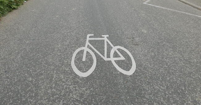 Ein auf den Asphalt aufgemaltes weißes Fahrradsymbol markiert einen Radschnellweg auf einer breiten Fahrbahn.