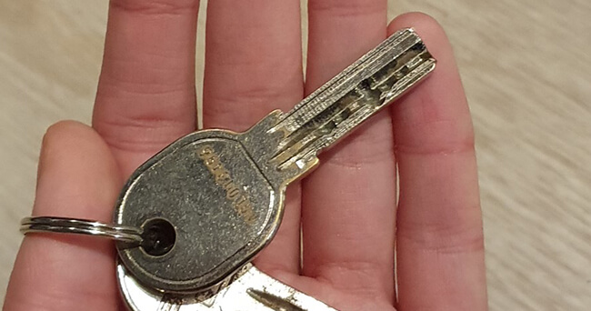 Eine Hand hält zwei Schlüssel, im Hintergrund eine helle Holzoberfläche.