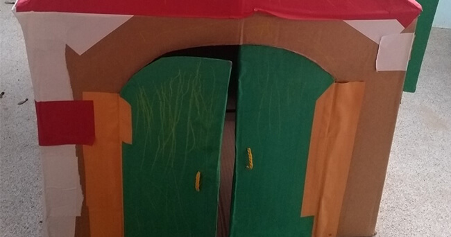 Kleine mobile Unterkunft mit grünem Doppeltür-Eingang, gefertigt aus bemaltem Material, dient als geschützter Schlaf- und Rückzugsort für obdachlose Menschen.