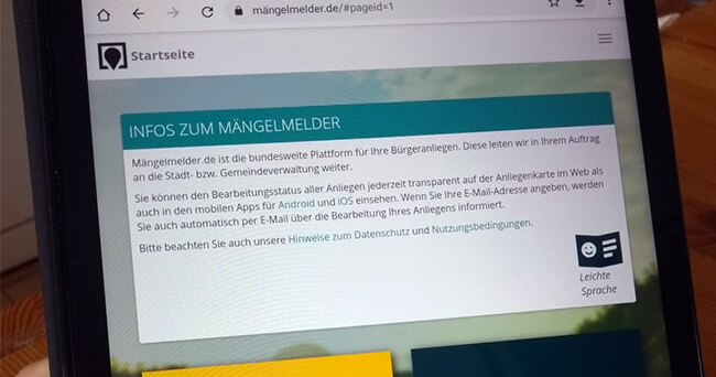 Nahaufnahme eines Tablet-Bildschirms mit geöffneter Webseite des bundesweiten Mängelmelders, auf der Informationen zur Meldung von Schäden und Mängeln angezeigt werden.