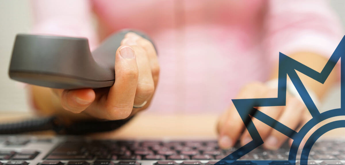 Frauenhände mit Telefon in der Hand vor einer Tastatur