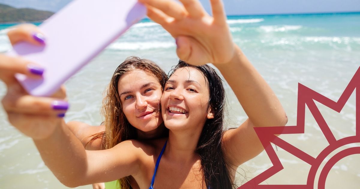 Facebook Post Urlaub Social Media. Zwei Junge Frauen machen ein Selfie am Strand.